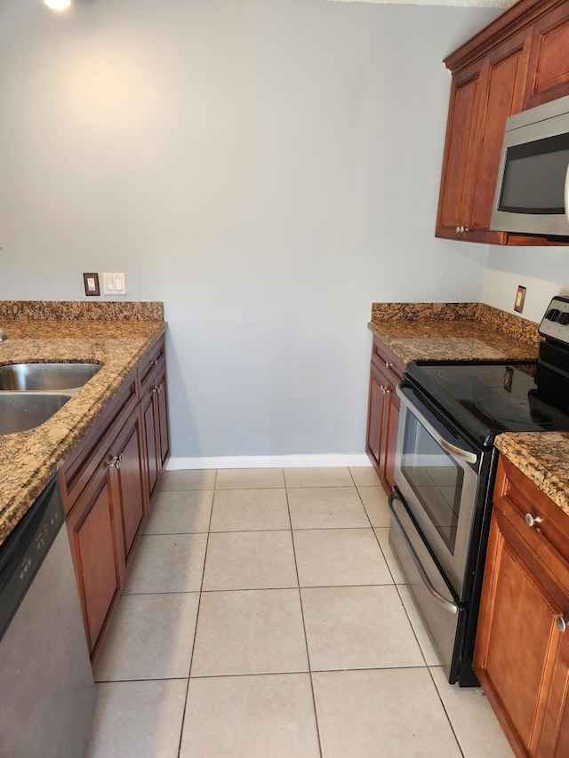 kitchen featuring light tile patterned floors, sink, stainless steel appliances, and stone countertops