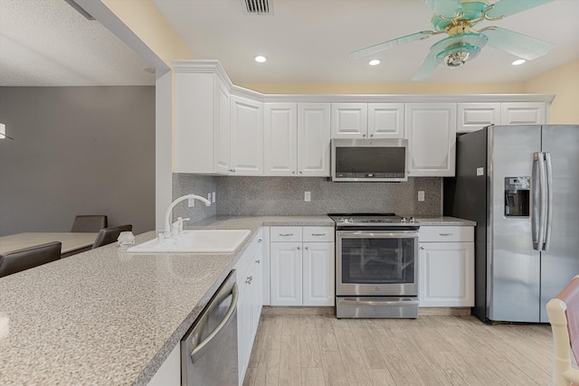 kitchen featuring appliances with stainless steel finishes, light wood-type flooring, white cabinetry, and backsplash