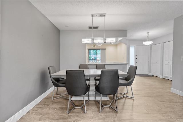 dining area featuring a textured ceiling and light hardwood / wood-style floors