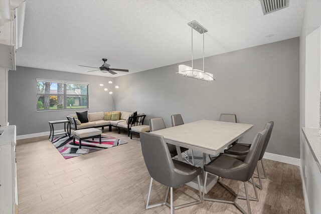 dining space featuring ceiling fan, light wood-type flooring, and a textured ceiling