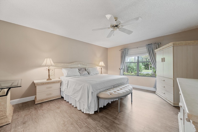 bedroom with ceiling fan, light hardwood / wood-style floors, and a textured ceiling