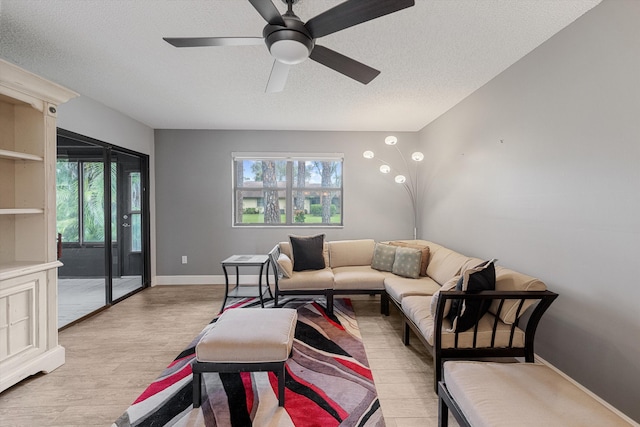 living room featuring ceiling fan, light hardwood / wood-style floors, and a textured ceiling