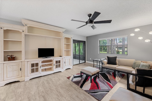 living room with ceiling fan, light hardwood / wood-style flooring, and a textured ceiling