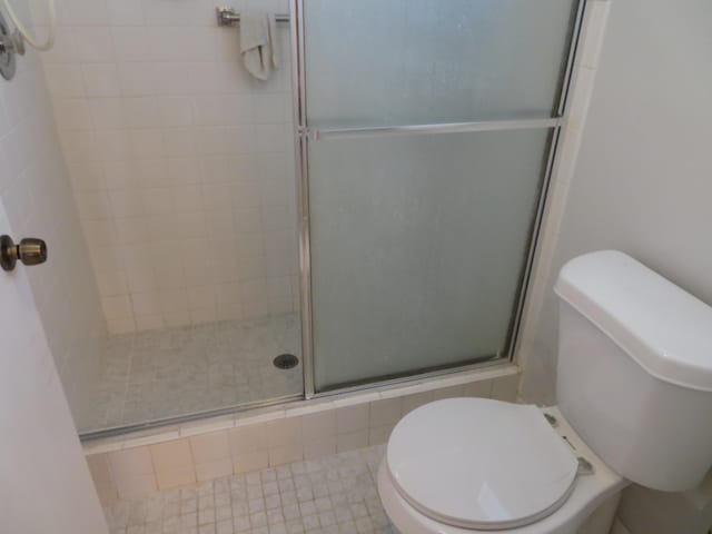 bathroom featuring a shower with shower door and toilet