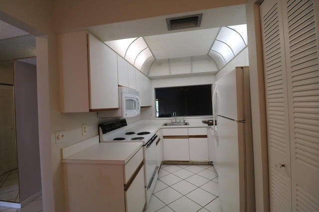 kitchen with sink, light tile patterned floors, white cabinets, and white appliances