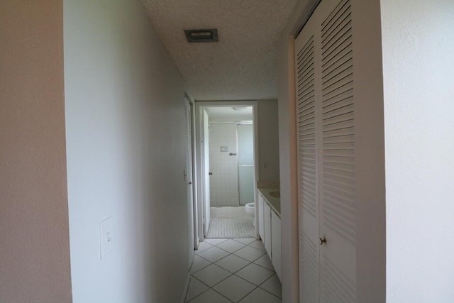 corridor featuring light tile patterned floors and a textured ceiling