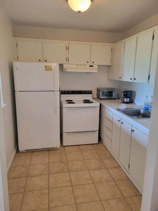 kitchen with white cabinets, white appliances, sink, and light tile patterned floors