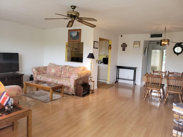 living room featuring ceiling fan with notable chandelier and light hardwood / wood-style floors