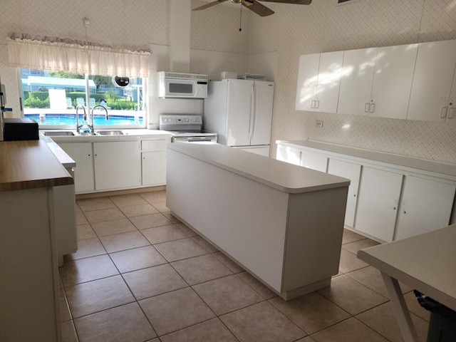 kitchen featuring white appliances, ceiling fan, sink, white cabinets, and a center island