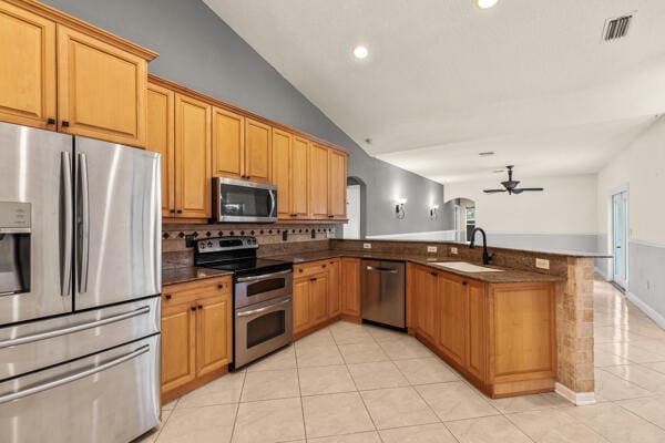 kitchen featuring sink, vaulted ceiling, ceiling fan, kitchen peninsula, and stainless steel appliances