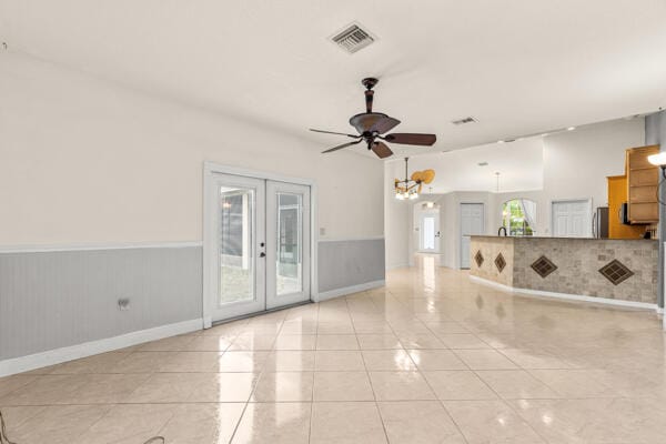 unfurnished living room featuring ceiling fan, french doors, and light tile patterned flooring