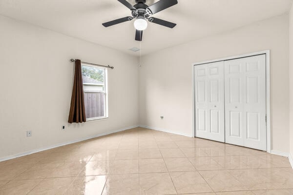 unfurnished bedroom with ceiling fan, a closet, and light tile patterned floors