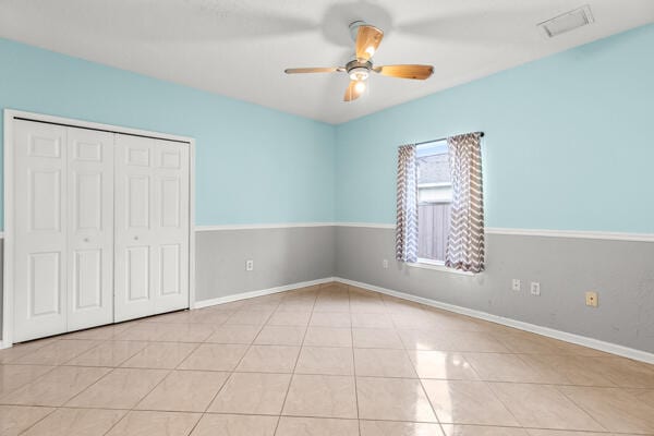 unfurnished bedroom featuring ceiling fan, light tile patterned floors, and a closet