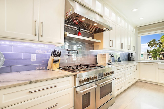 kitchen featuring white cabinets, range with two ovens, light stone countertops, and exhaust hood