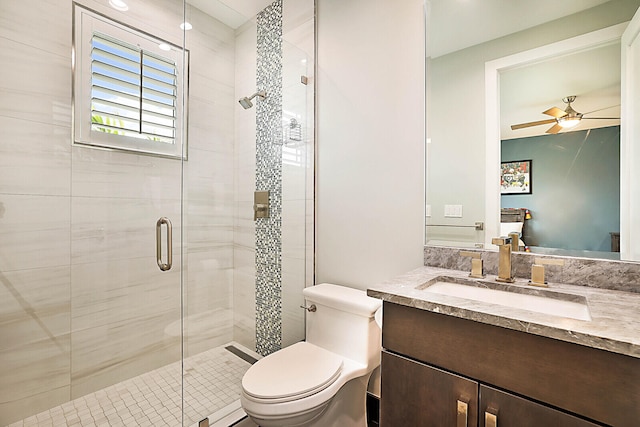 bathroom with ceiling fan, vanity, a shower with shower door, and toilet