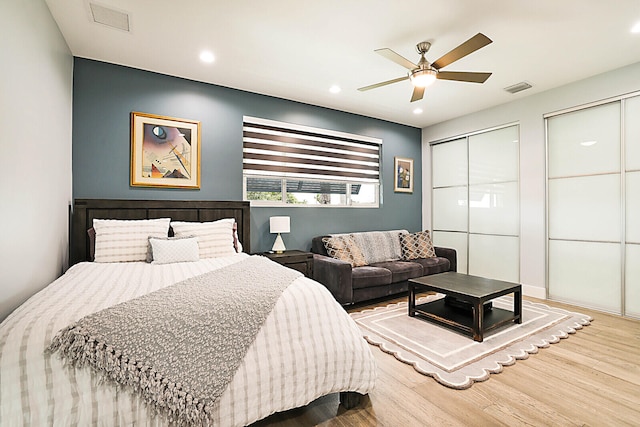 bedroom with hardwood / wood-style floors, two closets, and ceiling fan