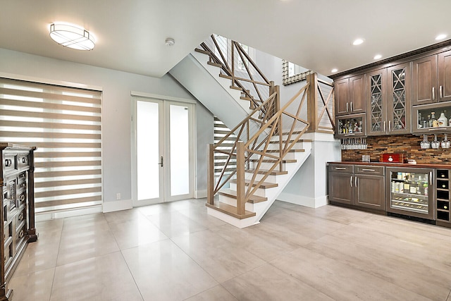 interior space featuring french doors, tasteful backsplash, dark brown cabinetry, beverage cooler, and light tile patterned flooring