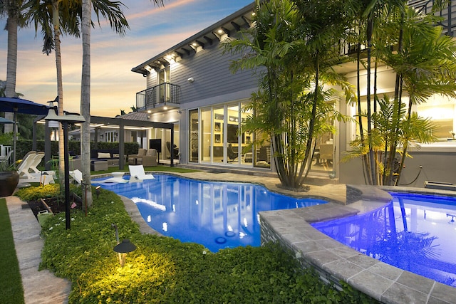 pool at dusk featuring a patio