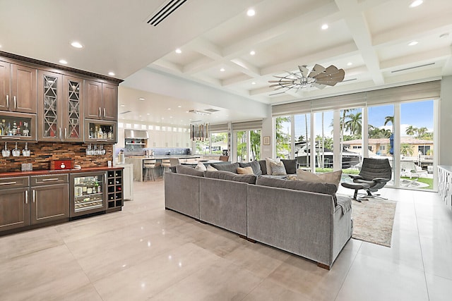 living room featuring bar, beamed ceiling, beverage cooler, and coffered ceiling