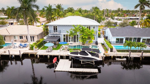 exterior space featuring a swimming pool with hot tub, a water view, a balcony, and a patio area