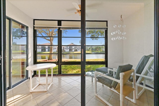 sunroom / solarium with a wealth of natural light, a water view, and ceiling fan