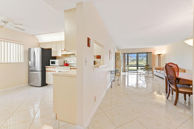 kitchen with light tile patterned floors, white appliances, a textured ceiling, and lofted ceiling