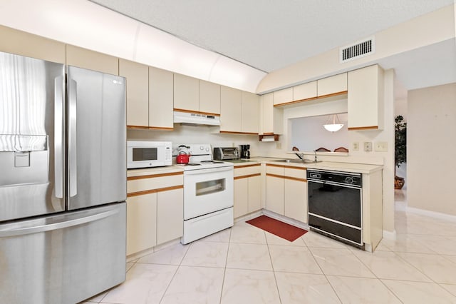 kitchen featuring white appliances, sink, and cream cabinets