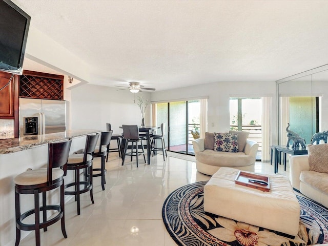 living room featuring ceiling fan, light tile patterned floors, and a textured ceiling