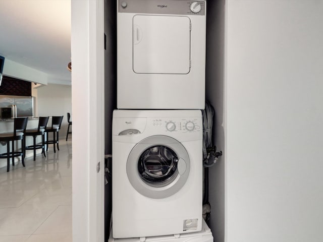 clothes washing area featuring stacked washer / dryer and light tile patterned flooring