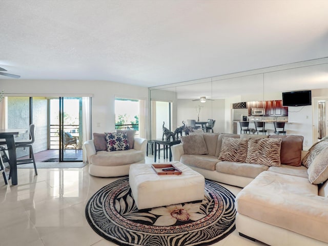 living room featuring light tile patterned floors, a textured ceiling, and ceiling fan