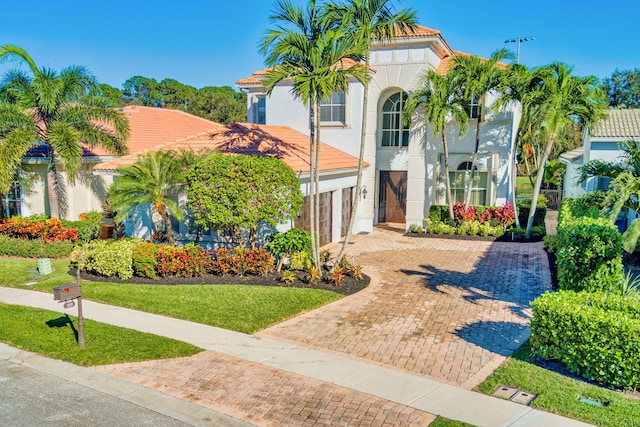 mediterranean / spanish-style home featuring a garage and a front yard