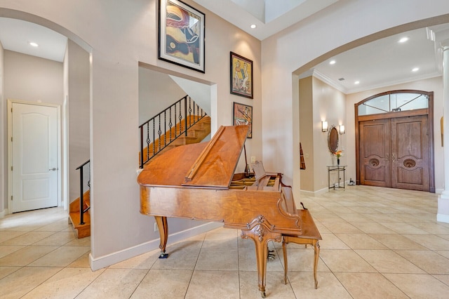 foyer featuring a high ceiling, crown molding, and light tile patterned flooring