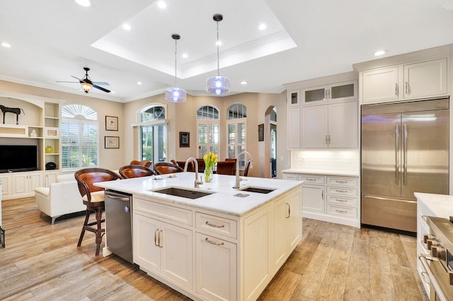 kitchen featuring a center island with sink, premium appliances, sink, and decorative light fixtures