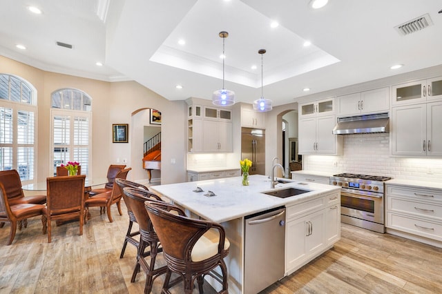 kitchen featuring a kitchen island with sink, sink, light hardwood / wood-style floors, and premium appliances