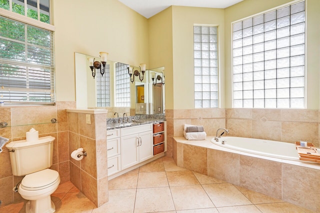 bathroom with tile patterned flooring, vanity, tile walls, and a wealth of natural light