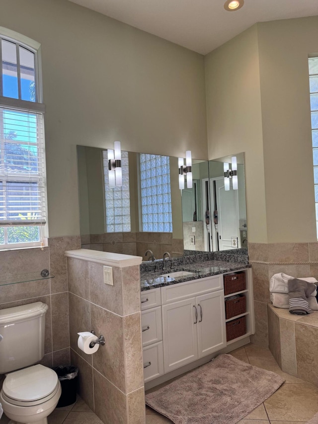 bathroom with tile patterned flooring, vanity, tile walls, and toilet