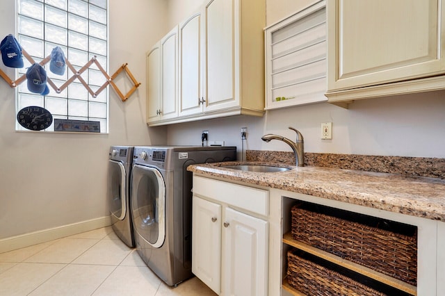 clothes washing area featuring washer and dryer, light tile patterned flooring, cabinets, and sink