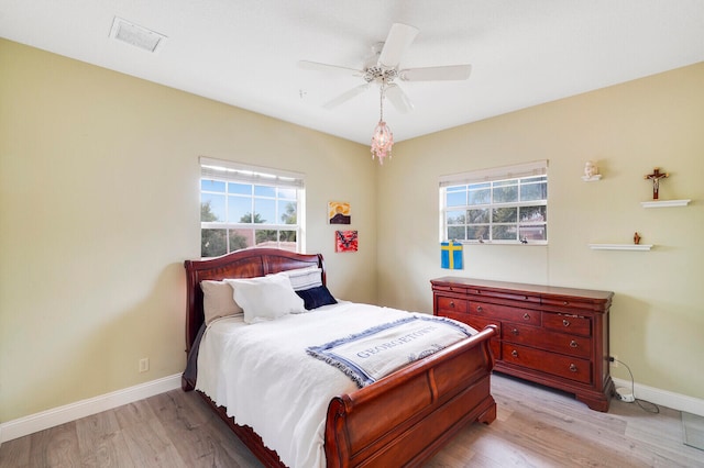 bedroom with ceiling fan, light hardwood / wood-style flooring, and multiple windows