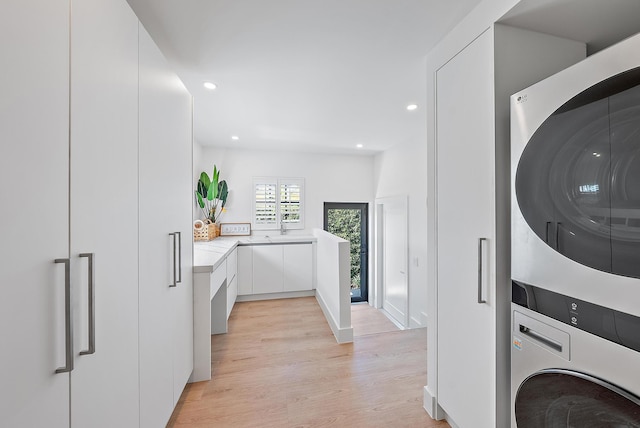 laundry area featuring light wood-type flooring and stacked washing maching and dryer