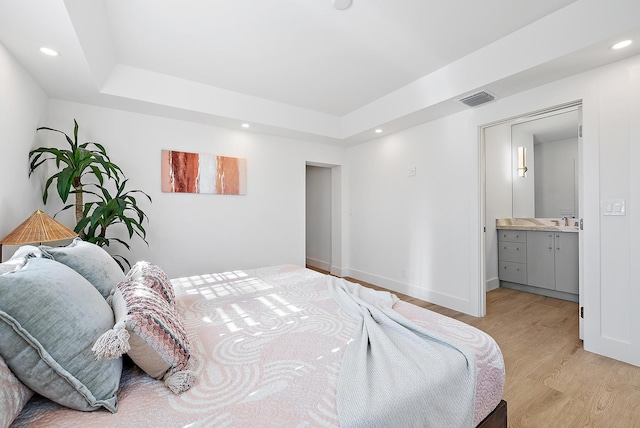 bedroom featuring light hardwood / wood-style floors, sink, and ensuite bath