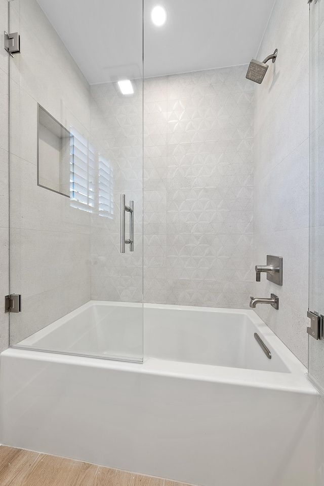 bathroom with hardwood / wood-style floors and combined bath / shower with glass door