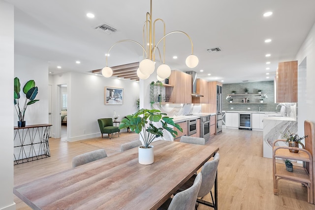 dining room featuring wine cooler, sink, and light hardwood / wood-style floors