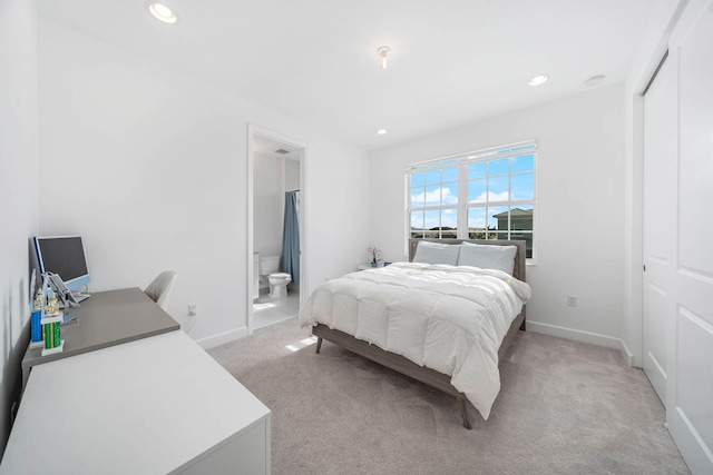 bedroom with ensuite bath, a closet, and light colored carpet