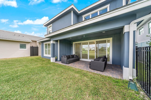 back of house featuring a lawn, an outdoor living space, and a patio area