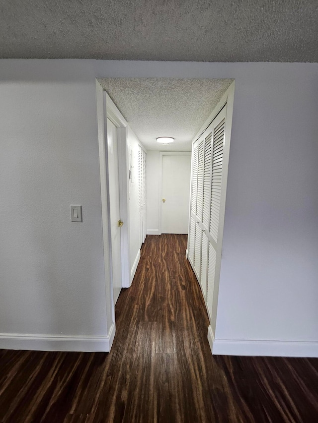 hall with dark hardwood / wood-style flooring and a textured ceiling