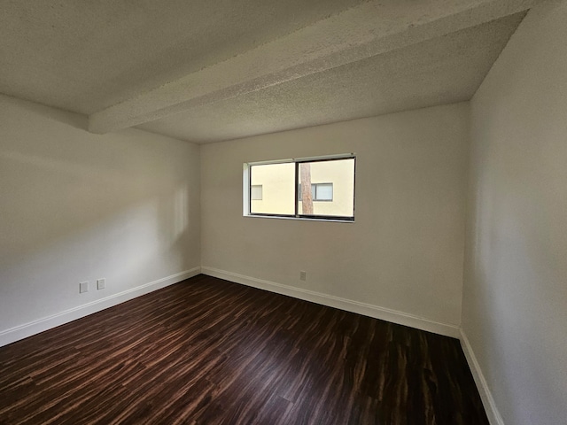 spare room with beamed ceiling, dark hardwood / wood-style floors, and a textured ceiling