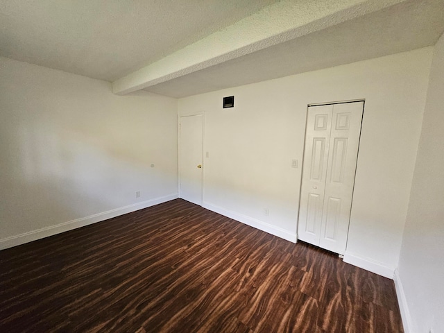 spare room with a textured ceiling and dark wood-type flooring