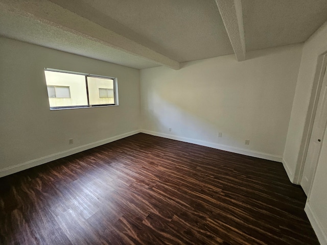 empty room with beamed ceiling, a textured ceiling, and dark hardwood / wood-style floors