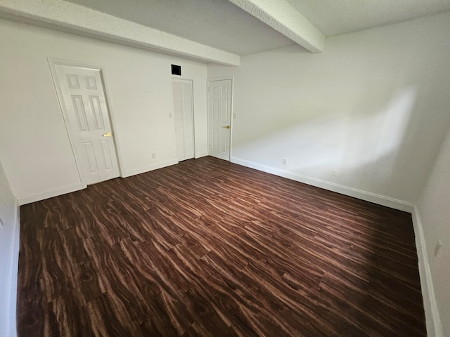 spare room featuring beam ceiling, a textured ceiling, and dark hardwood / wood-style floors