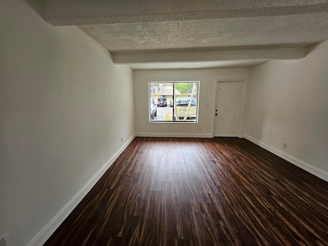 unfurnished room featuring beam ceiling, dark hardwood / wood-style flooring, and a textured ceiling